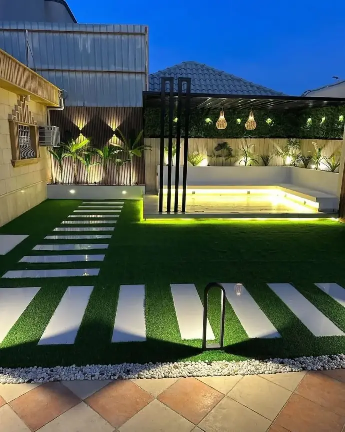 Pathway with green lawn and vertical plant walls at night